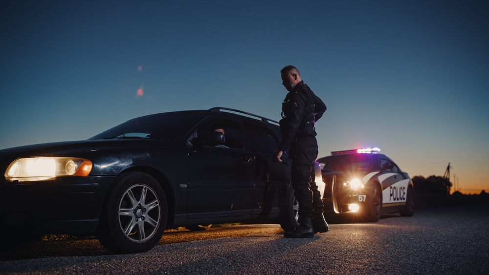 An image depicting an individual in the driver's seat being arrested for an intoxicated DWI offense under Indiana laws, highlighting the risk of losing driving privileges and potential jail time.