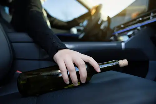 Woman Holding steering wheel with Bottle