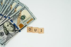 How a DUI affects auto insurance rates, money with letters spelling DUI